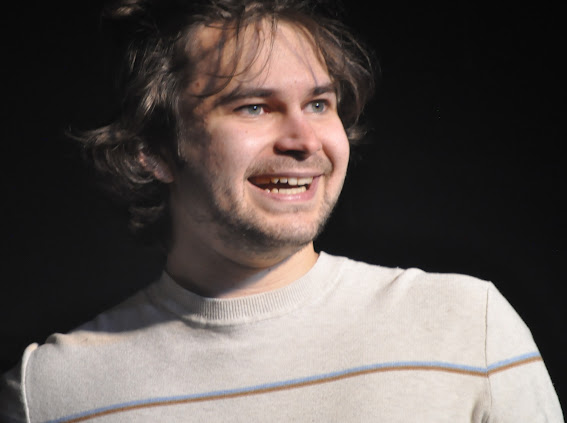 Liam Gibler smiling on stage in warm light